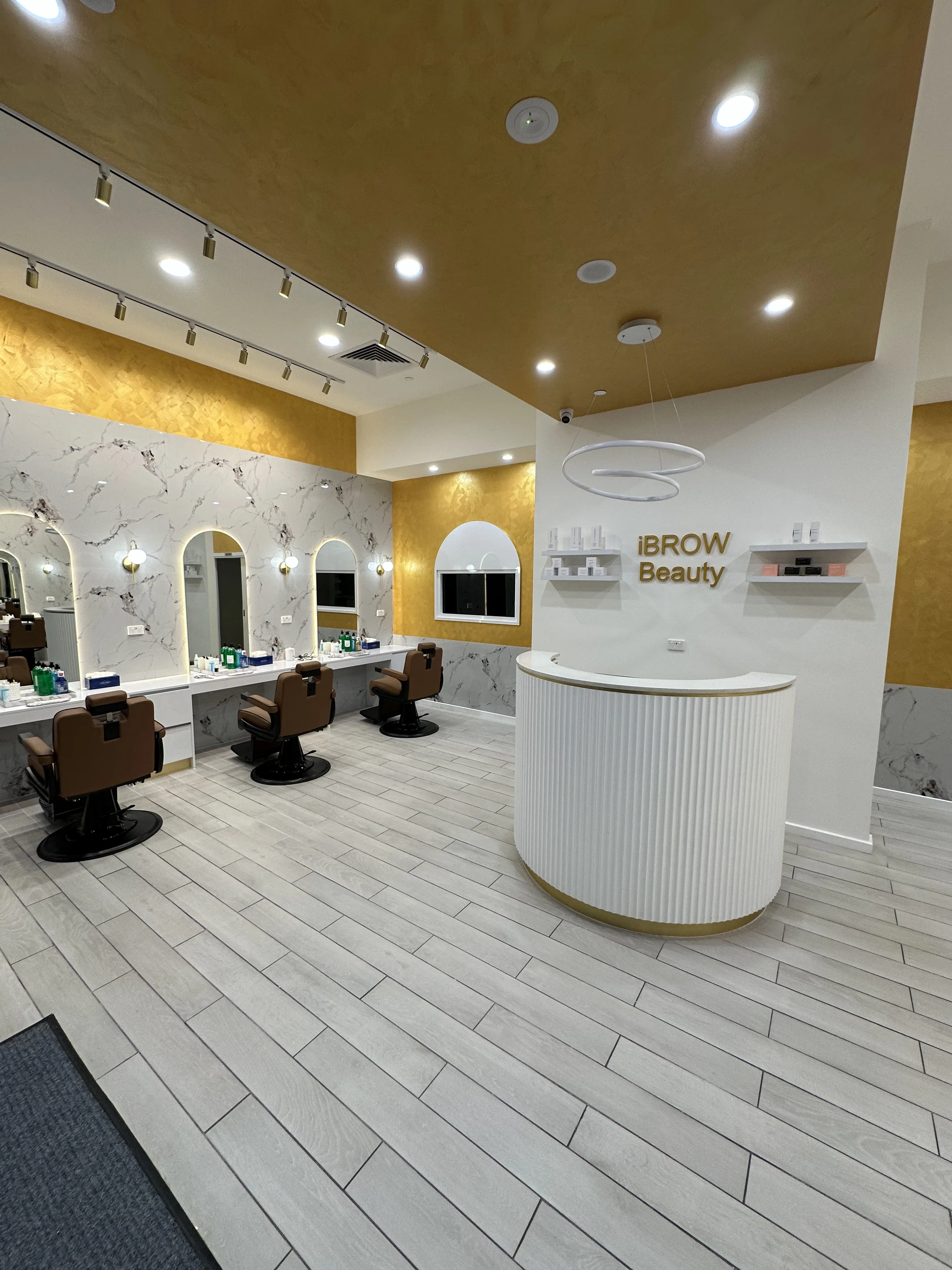 Reception plinth with 3-D gold iBROW Beauty sign and twin-ring halo pendant